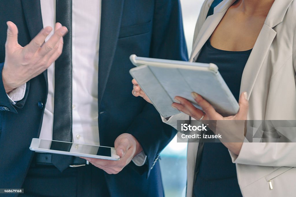 Two business people using digital tablets Businesswoman and businessman in formal outfits holding digital tablets. Close up of hands. Unrecognizable people. 2015 Stock Photo
