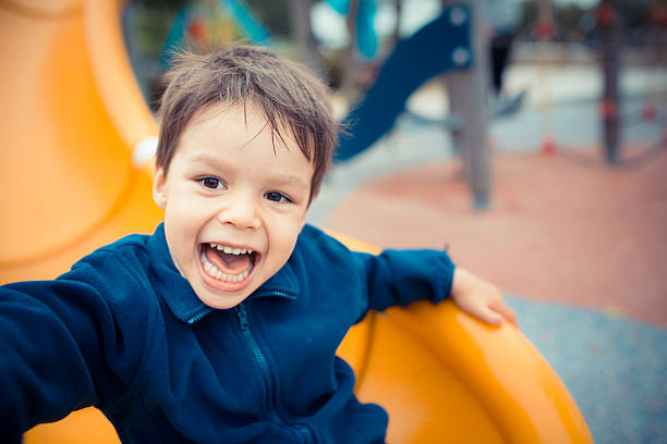 喜んで遊ぶかわいい男の子に、滑り台 - preschooler portrait family outdoors ストックフォトと画像