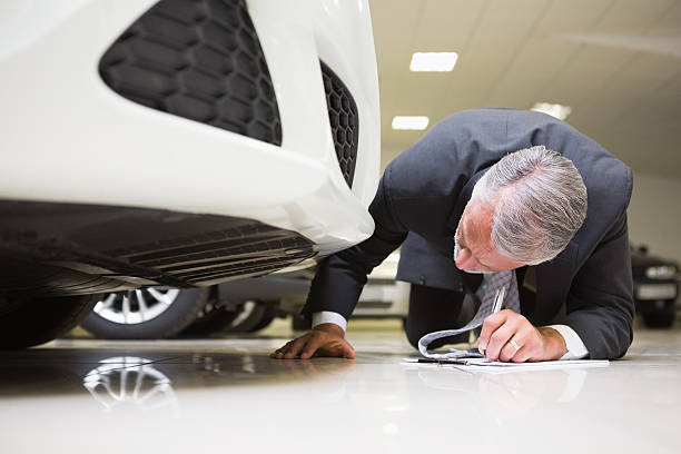 istock Businessman looking under the car while writing on clipboard 468679574