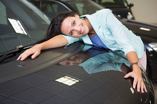 istock Smiling woman hugging a black car 468679950