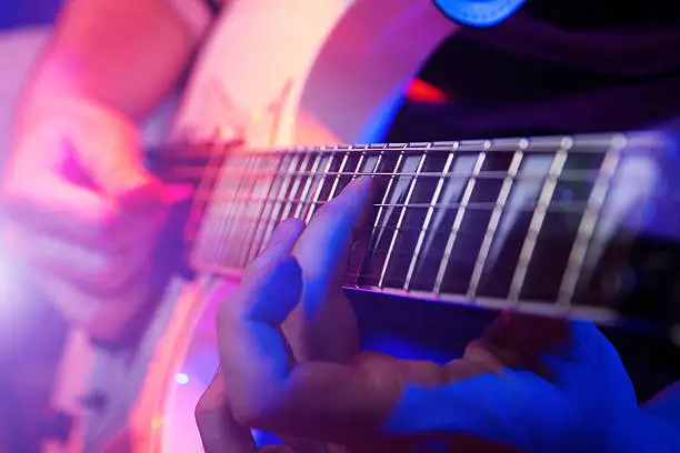 Photo of Close up of hands playing a guitar