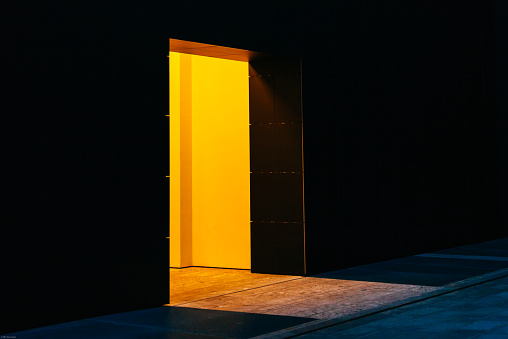 A yellow bright open door is the entrance of a dark building, Milan, Italy. This photo reminds mistery and opportunities of entering through the door