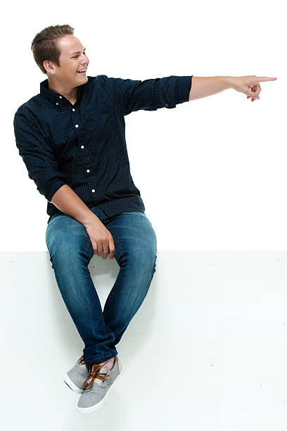 istock Smiling casual man on box and pointing away 468686832