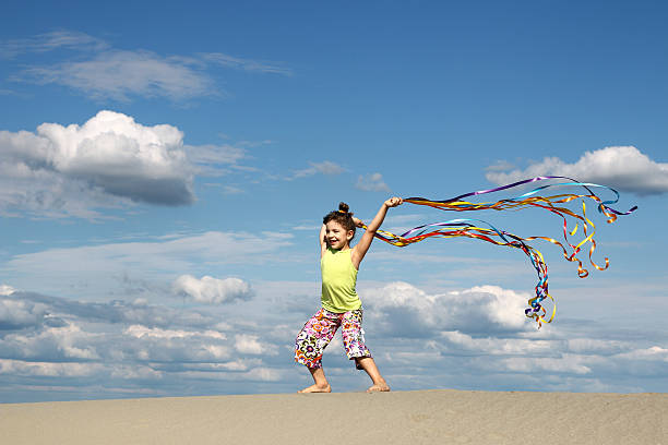 Little girl running with flying kite on the big deserted beach during a travel with family - Little girl playing with kite butterfly on sea shore in a spring sunny day