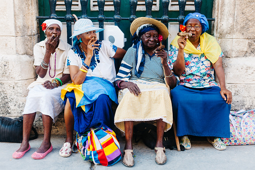 Havana, Cuba - September 7, 2014: A group of colorful dressed women smoking cigars in the streets of Havana, Cuba