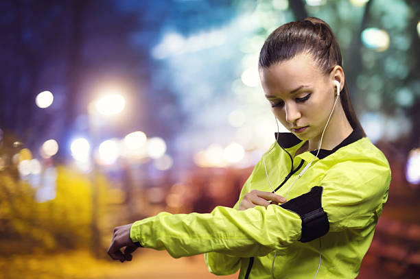 istock Woman jogging outside at night using technology armband 468697788
