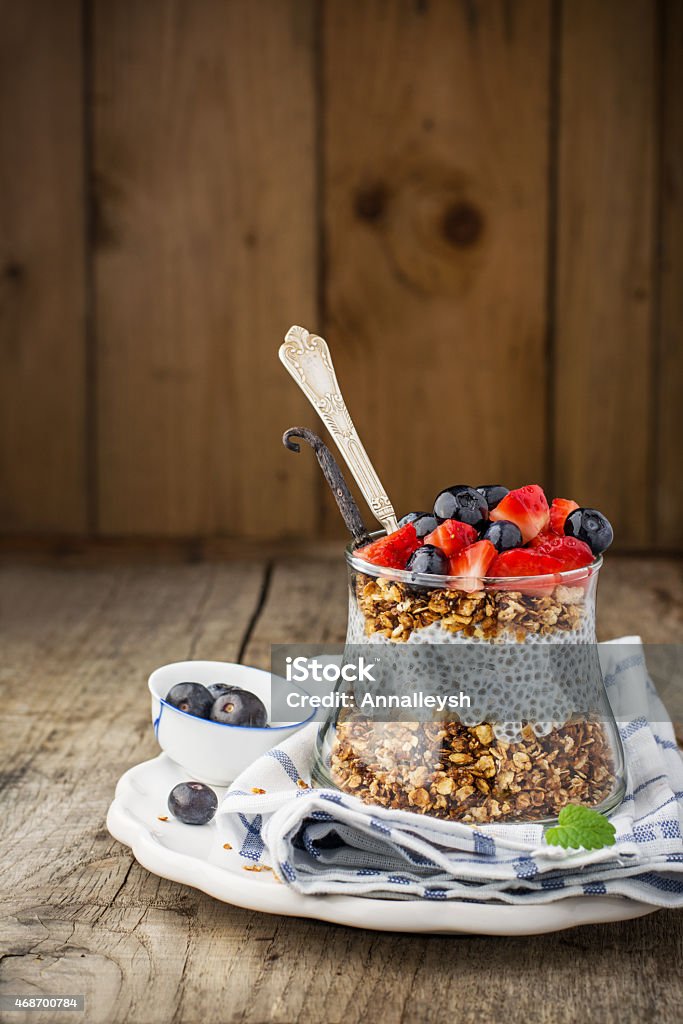 Chia Seed Pudding Chia Seed Pudding and caramel oat flakes, blueberries and strawberries in a transparent glass on a wooden background. Selective focus. Concept of healthy food 2015 Stock Photo