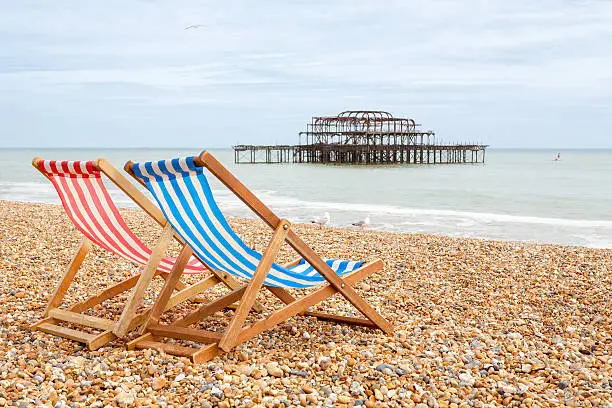 Two deckhairs on Brighton beach with West Pier behind. Brighton, East Sussex, England