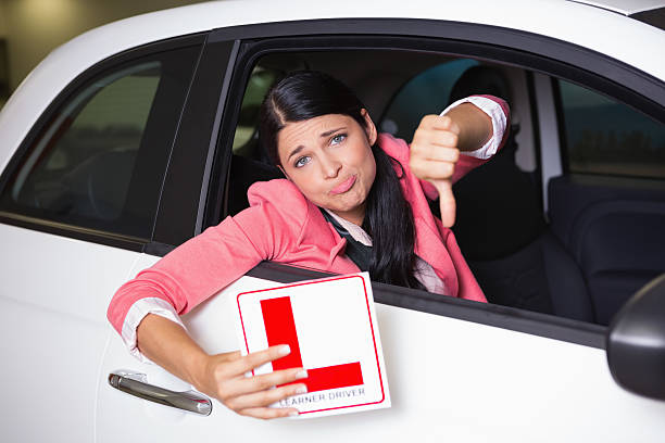 istock Woman gesturing thumbs down holding a learner driver sign 468708526