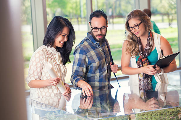 istock Group of young businesspeople studying architecture model and blueprints together 468710788