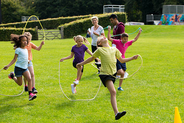 Skipping Rope Race Young children racing with skipping ropes as an adult watches jump rope stock pictures, royalty-free photos & images