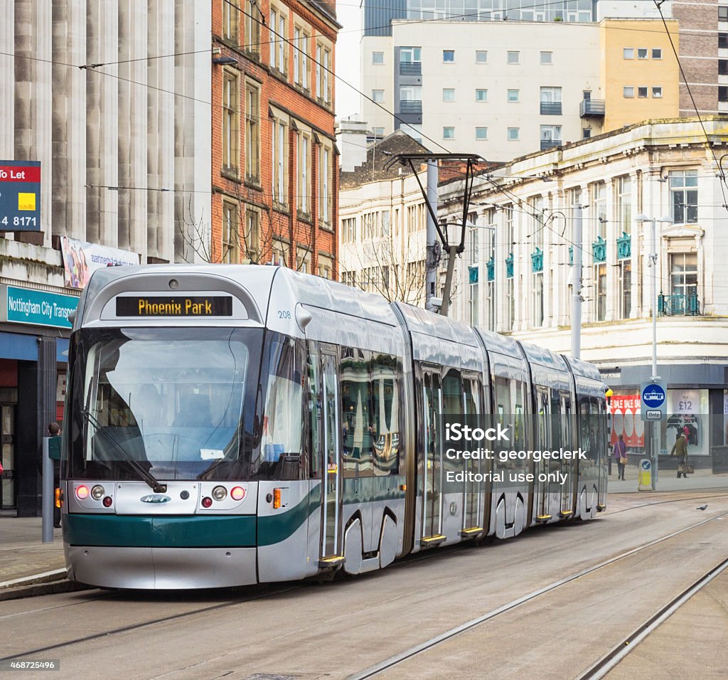 Tram in Nottingham Nottingham, UK - March 26, 2014: A modern tram at a stop in Nottingham's city centre, with people walking on the surrounding pavements. Cable Car Stock Photo