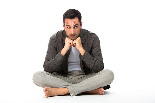 Thoughtful man seated on the floor with the hands under his chin