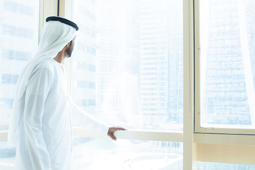 Arab hombre de negocios mirando a través de la ventana de negocios edificio photo