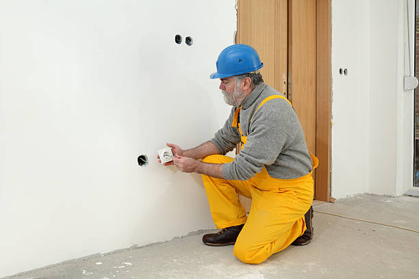 Electrician at construction site install electrical plug Electrician installing electrical plug at wall and using voltage testing screwdriver cable tester stock pictures, royalty-free photos & images