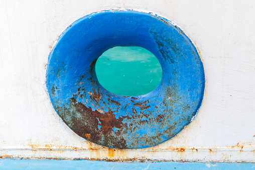 Empty blue hawse in old white rusted ship hull