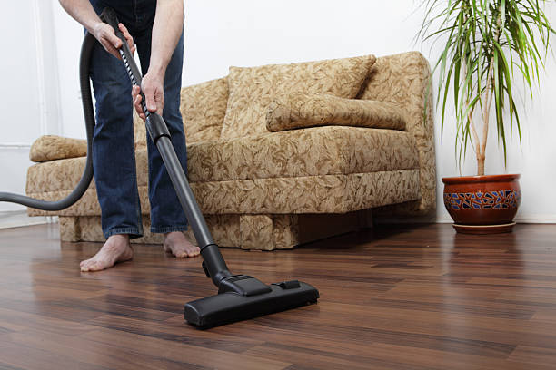 istock Man vacuuming a floor in a living room 468733052