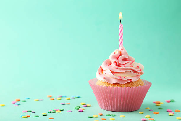 istock Tasty cupcake with candle on green background 468733556