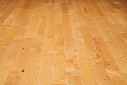 A basketball court floor made of maple hardwood viewed at a low angle