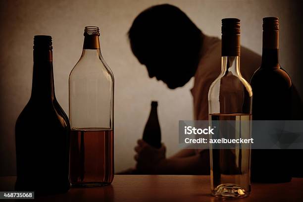 Alcohol Bottles With The Silhouette Of An Alcoholic Man Stock Photo - Download Image Now