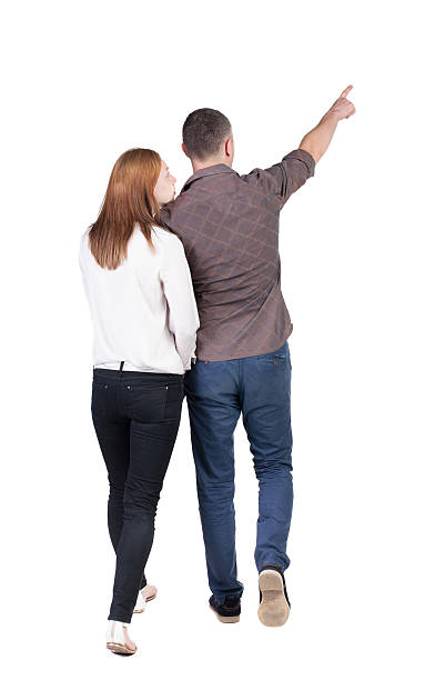 istock Back view of walking young couple (man and woman) pointing. 468738974
