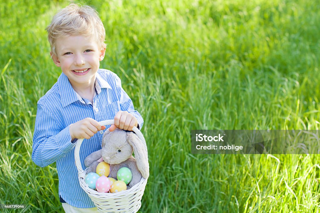 easter time smiling cheerful little boy holding basket with colorful easter eggs and bunny toy at spring time in the park 2015 Stock Photo