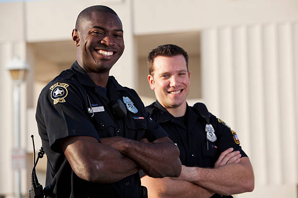 Police officers Multi-ethnic police officers (20s). Focus on African American man. police force smiling officer stock pictures, royalty-free photos & images