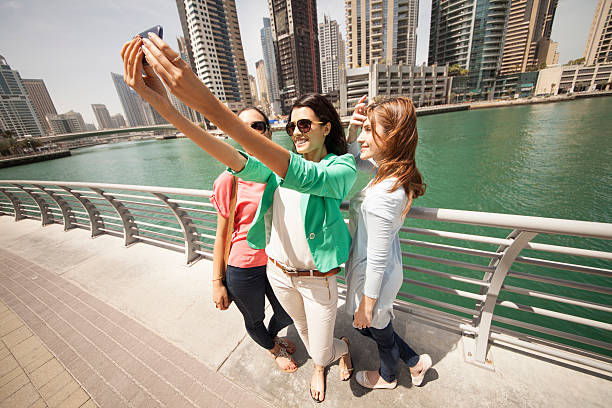 istock Smiling women taking selfie against cityscape 468744696