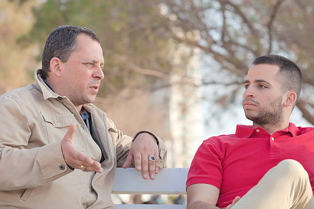 Shot of young adult man and his father talking together outside