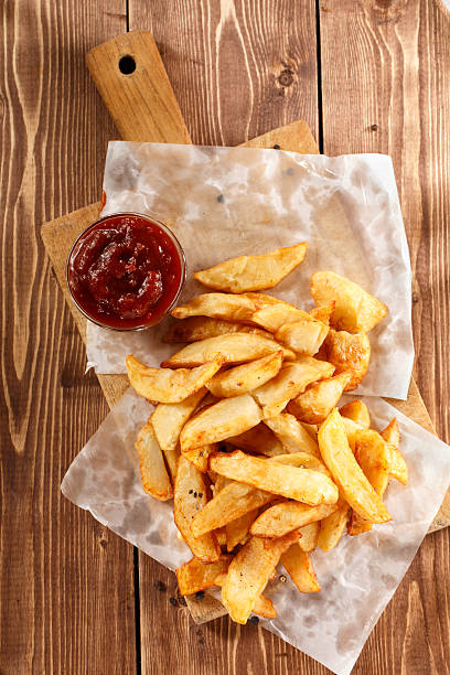 istock Fried Potatoes on old wooden cutting board with bowl ketchup. 468755764