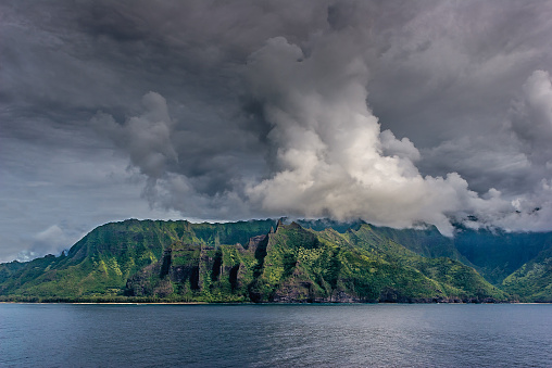 Clouds rolling over the rugged, lush green cliffs and narrow valleys of Na Pali Coast on the island of Kauai, Hawaii