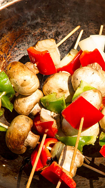 Brochette with vegetables on the fire, camping. Brochette with chicken meat, pepper, champignon, onion and several vegetables on a wok on the fire camping. Food. delaware chicken stock pictures, royalty-free photos & images