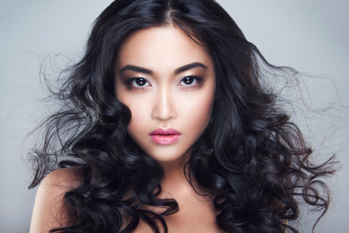 Young and beautiful asian woman with curly hair. Pink lips. Black eyes.