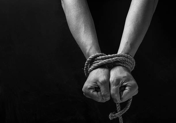 Hands of a missing kidnapped Hands tied with rope on a black background. kidnapping photos stock pictures, royalty-free photos & images