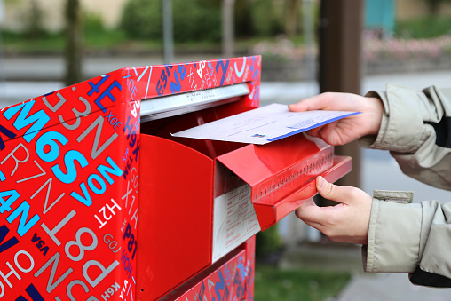 Coquitlam, BC Canada - April 24, 2014 : Hand sending a tax report letter in a red mail box 