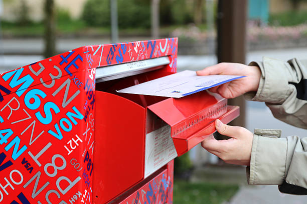 Hand sending tax report letter in red mail box stock photo