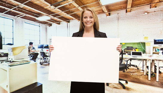 Smiling businesswoman holding placard in officehttp://www.twodozendesign.info/i/1.png