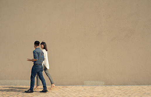 Businessman and his female colleague walking along the wall