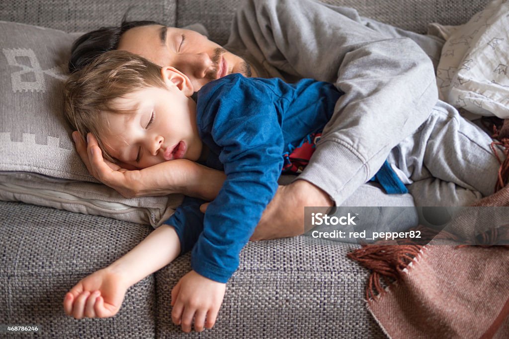 Father and son napping on the couch portrait of father and son fallen asleep together on the couch Sleeping Stock Photo