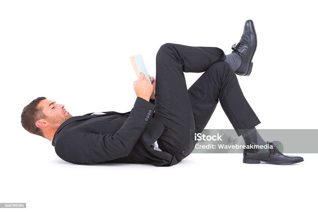 Businessman lying on the floor reading book Businessman lying on the floor reading book on white background Businessman Stock Photo