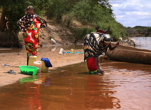 Garsen, Kenya - April 3, 2012: Somali women, recognisable by their brightly coloured dresses, are washing in the Tana river 