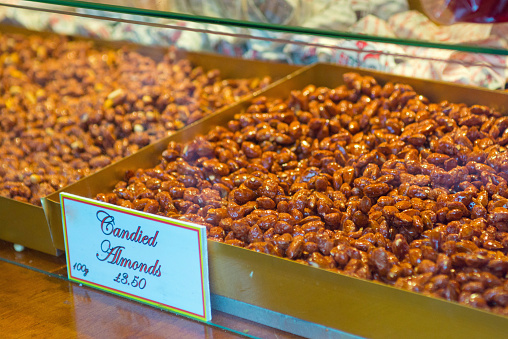 Pile of chocolate almonds in a shelving display. Generic sign for candied almonds.