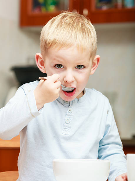 istock Boy kid child eating corn flakes breakfast at the table 468794093