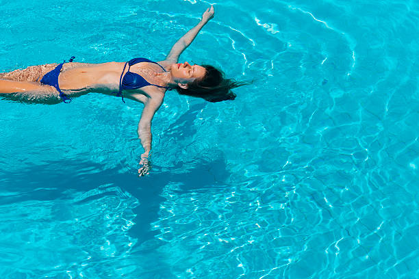Calm woman floating in the pool in a sunny day