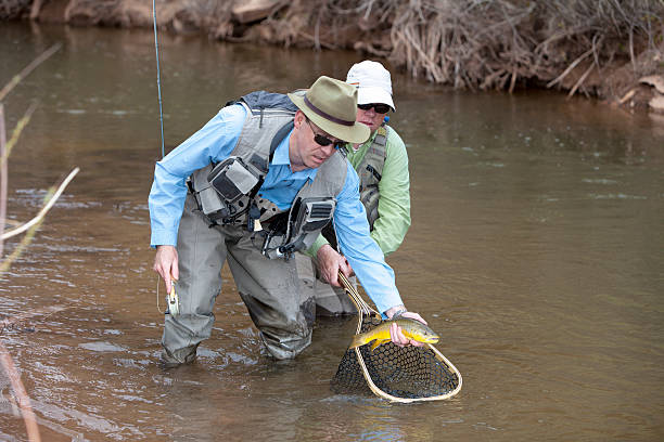 istock Guide helps land a trout while fishing on a river 468800954
