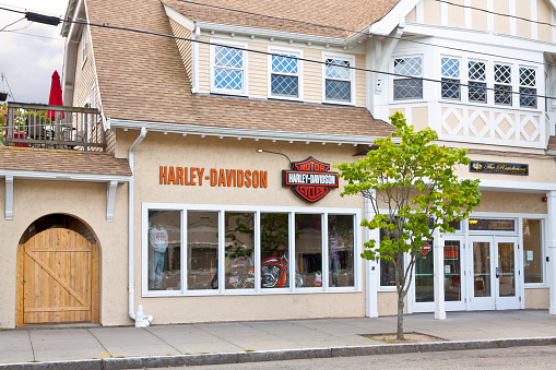 Hyannis, MA, USA - September 16, 2014: The Harley-Davidson Motorcycles Store on Main Street in Hyannis. Cape Cod, Massachusetts., USA. The Harley-Davidson Motorcycle is on dispaly in the store window. Green trees are in foreground. Canon EF 24-105mm f4L IS lens.
