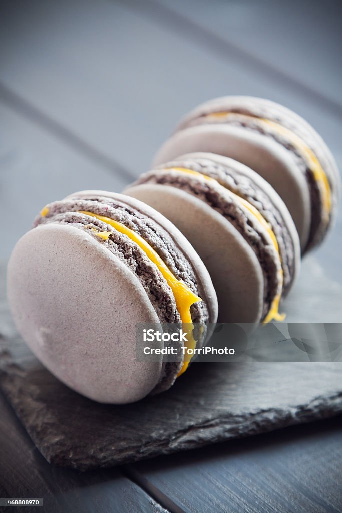 Gray macaroons on dark grey background Gray macaroons with yellow cream on stone board placed on dark wooden background. Shallow focus 2015 Stock Photo