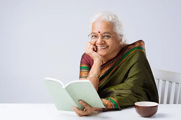 Cheerful Indian woman in glasses reading a book