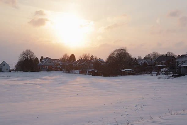 Sun setting over Swedish countryside of Skane in Winter with houses in background.