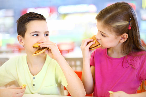 istock Two kids eating burgers. 468821335